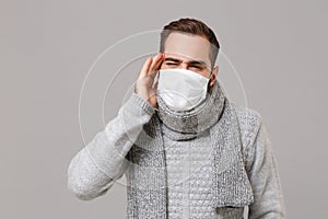 Young man in gray sweater, scarf isolated on grey background. Healthy lifestyle, ill sick disease treatment, cold season