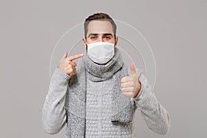 Young man in gray sweater, scarf isolated on grey background. Healthy lifestyle ill sick disease treatment, cold season