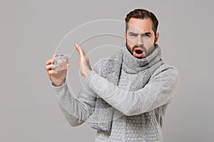 Young man in gray sweater, scarf isolated on grey background. Healthy lifestyle ill sick disease treatment cold season