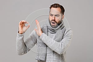 Young man in gray sweater, scarf isolated on grey background. Healthy lifestyle ill sick disease treatment cold season