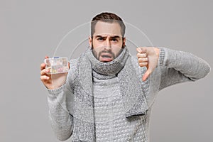 Young man in gray sweater, scarf isolated on grey background in studio. Healthy lifestyle, ill sick disease treatment