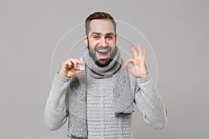 Young man in gray sweater, scarf isolated on grey background studio portrait. Healthy lifestyle ill sick disease