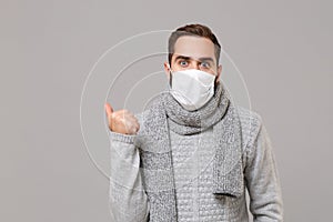 Young man in gray sweater, scarf isolated on grey wall background. Healthy lifestyle, ill sick disease treatment, cold