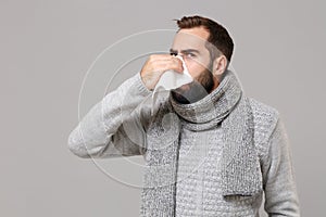 Young man in gray sweater, scarf isolated on grey wall background. Healthy lifestyle, ill sick disease treatment, cold