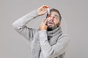 Young man in gray sweater, scarf isolated on grey wall background studio portrait. Healthy lifestyle, ill sick disease