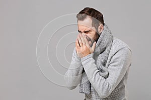 Young man in gray sweater, scarf posing isolated on grey background. Healthy lifestyle, ill sick disease treatment, cold