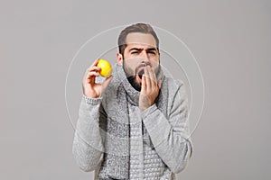 Young man in gray sweater, scarf posing isolated on grey background in studio. Healthy lifestyle, ill sick disease
