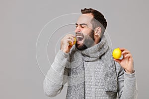 Young man in gray sweater, scarf posing isolated on grey wall background, studio portrait. Healthy fashion lifestyle