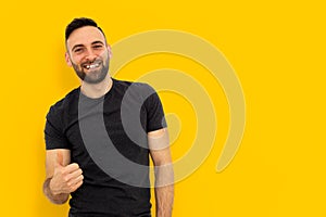 Young man in gray t-shirt on yellow colored background shows thumb up - concept of positivity, optimism, hope and goal achievement