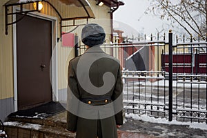 Young man in greatcoat stands near checkpoint photo