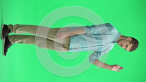 A young man on a green background shows an ok sign in full growth