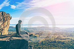 Young man in green sportswear is sitting on cliff's edge