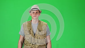 Young man in a grey t-shirt, sleeveless shirt and hat going against a green background. Slow motion.