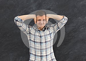 Man covering his ears with his hands and grimacing