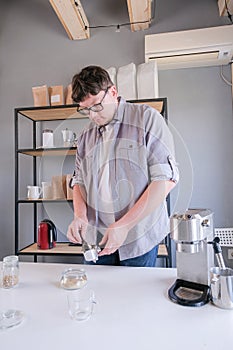 young man grinding coffee at home , making coffee in the morning