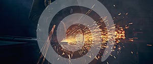 Young man grinding metal on steel pipe with flash sparks.