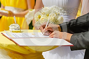 A young man, the groom, signs the marriage documents. Wedding ceremony.