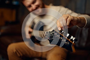 Young man guitarist tune guitar before playing