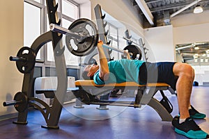 Young Man In Gym Exercising Chest On The Bench Press with barbell