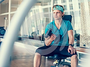 Young man in gym hall training with dumbbell