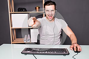 Young man or hacker in headset and eyeglasses with pc computer playing game and streaming playthrough or walkthrough video pointed
