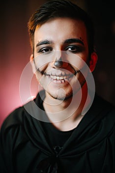 Young man with Halloween make-up smiling at the camera