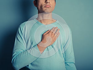 Young man with hand on his chest