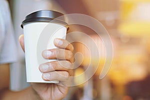 Young man hand holding Paper cup in the coffee shop