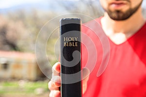 Man hand Holy Bible in nature