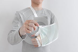 Young man with hand injured wearing splint, broken arm, showing empty blank card