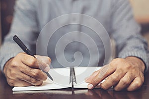 young man hand are sitting using pen writing Record Lecture note pad diary into the book