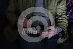 Young man hand using smart phone and writing on notepad. Business plan concept. Businessman holding notebook, using smart mobile p