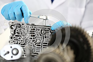 Young man hands repairing car gearbox parts