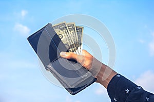 Young man hands showing dollar bills . dollar bills on sky background.