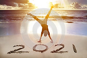 Young man handstand on the beach.happy new year 2021 concept