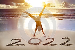Young man handstand on the beach.  happy new year 2022 concept