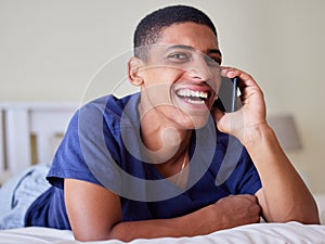 Young man, happy conversation and phone call in bedroom, share funny story and laughing with contact at home. Mobile app