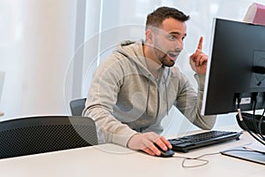 Young man happy and exalted because he has found the solution in front of the computer screen