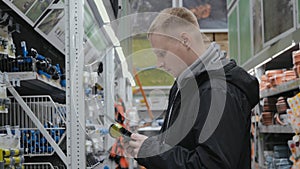 Young man in a hardware store. A man in a store chooses accessories for watering the lawn. Construction supermarket. Big