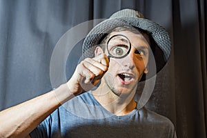 Young man has fun enlarging his eye with a magnifying glass