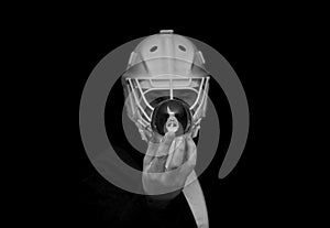 A young man has a goalie helmet on his head and holds a crystal ball with his reflection.