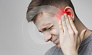 Young man has sore ear, suffering from otitis photo