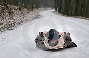 The young man in the hat lays along the road to snow in the winter