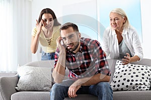 Young man having argument with wife and mother-in-law photo