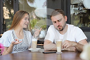 Young man having boring date with talkative girl in cafe