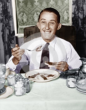 Young man having breakfast and smiling