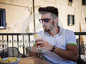 Young man having cocktail at outdoor bar