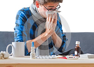 Young man is having a cold, sneezing in a tissue