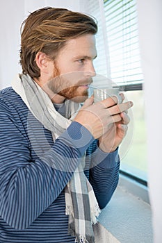 young man having cup coffee while looking out