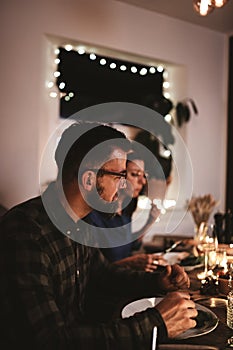 Young man having dinner with friends around a candlelit table